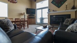 A living room with a fireplace, a television, and a dining area with wooden furniture. - 410 Storm Meadows Club C Apartment 2 (Steamboat Springs)