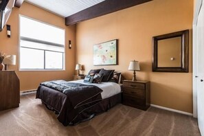 Une chambre à coucher avec un grand lit, une fenêtre, un tableau, un miroir et une table de chevet.