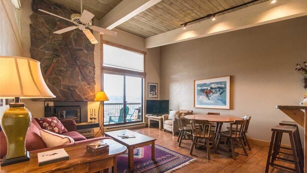 A spacious living room with a fireplace, a dining area, and a large window providing natural light.