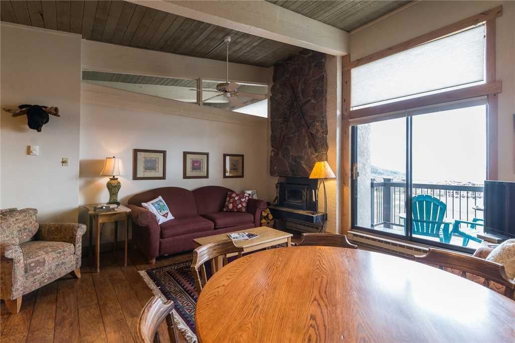 A cozy living room with a fireplace, a dining table, and a large window with a view.