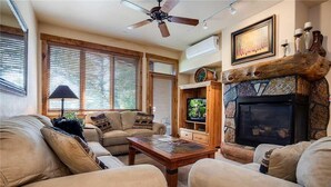 Una sala de estar acogedora con chimenea, ventilador de techo y televisión.