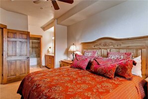 Ein Schlafzimmer mit einem großen Bett, einem Holz-Kopfteil und einem Nachttisch mit Lampe.