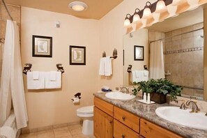 A bathroom with two sinks, wooden cabinets, a large mirror, and framed pictures on the wall.