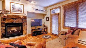 A cozy living room with a stone fireplace, a flat-screen TV, and comfortable seating. - 3109 Champagne Lodge, Trappeur's Crossing Apartment 3 (Steamboat Springs)