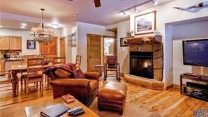 A cozy living room with a fireplace, wooden furniture, and a television. - 3109 Champagne Lodge, Trappeur's Crossing Apartment 3 (Steamboat Springs)