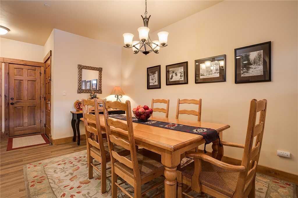 A dining area with a wooden table and chairs, a chandelier, and framed pictures on the wall.