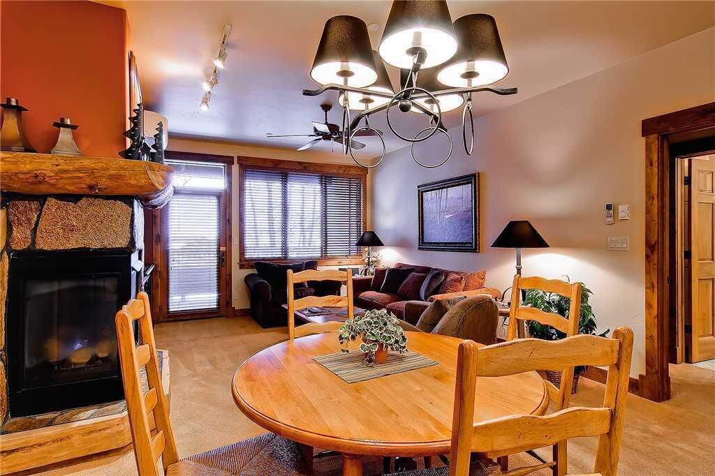 A cozy living room with a fireplace, wooden dining table, and comfortable seating.