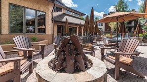 An outdoor patio with Adirondack chairs, a fire pit, and umbrellas.