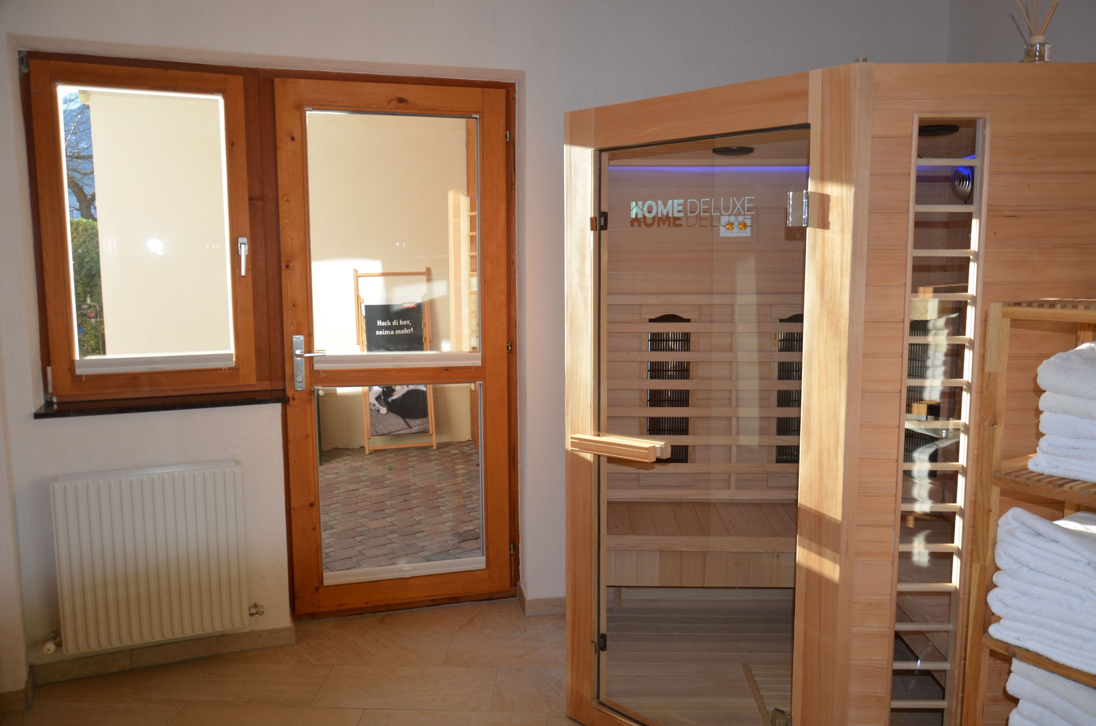 A sauna room with wooden doors, a tiled floor, and a towel rack.