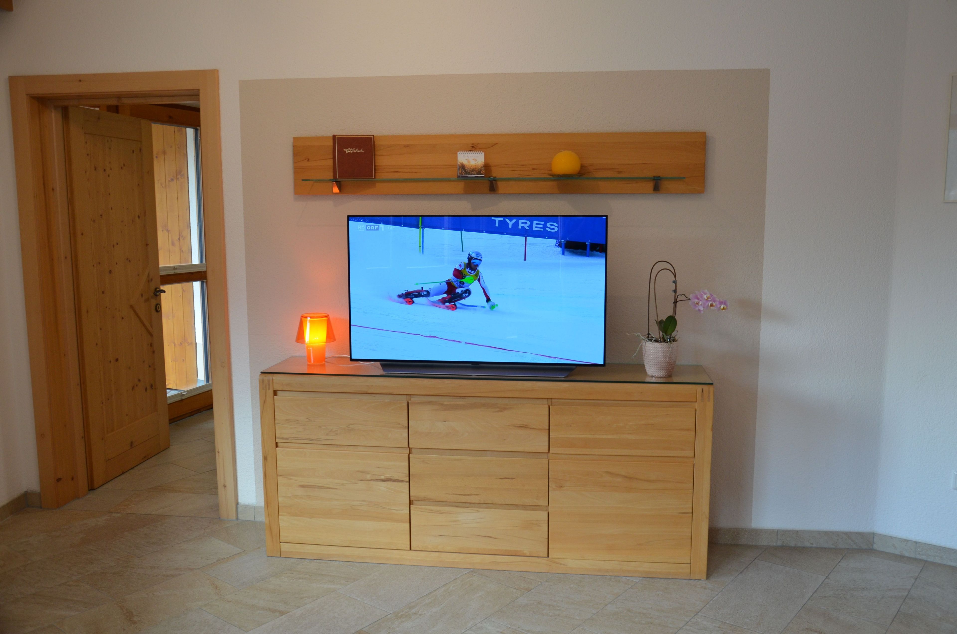 Un televisor sobre un mueble de madera con un estante encima.