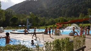 A pool area with water slides and a fountain, surrounded by greenery and hills. - Apart Franzi Top 1 - Apart Franziska (Kauns)