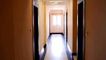 En hotellkorridor med ett ljust golv, beige väggar och dörrar på båda sidor.