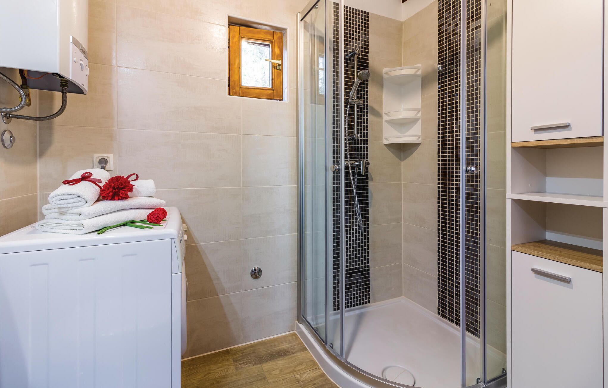 Een moderne badkamer met een douche met glazen wand, een ingebouwd toilet en een witte wasmachine.