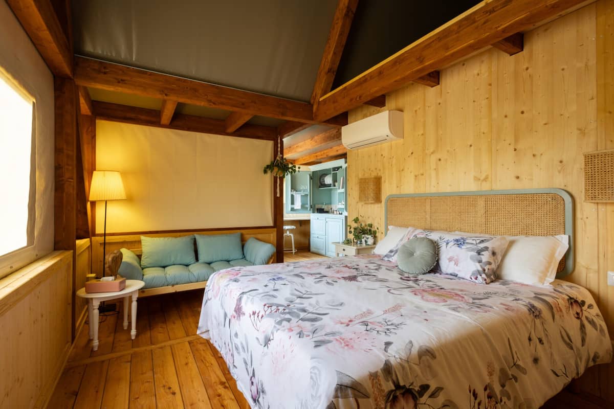 Une cabane en bois avec un lit, une petite table et un banc.
