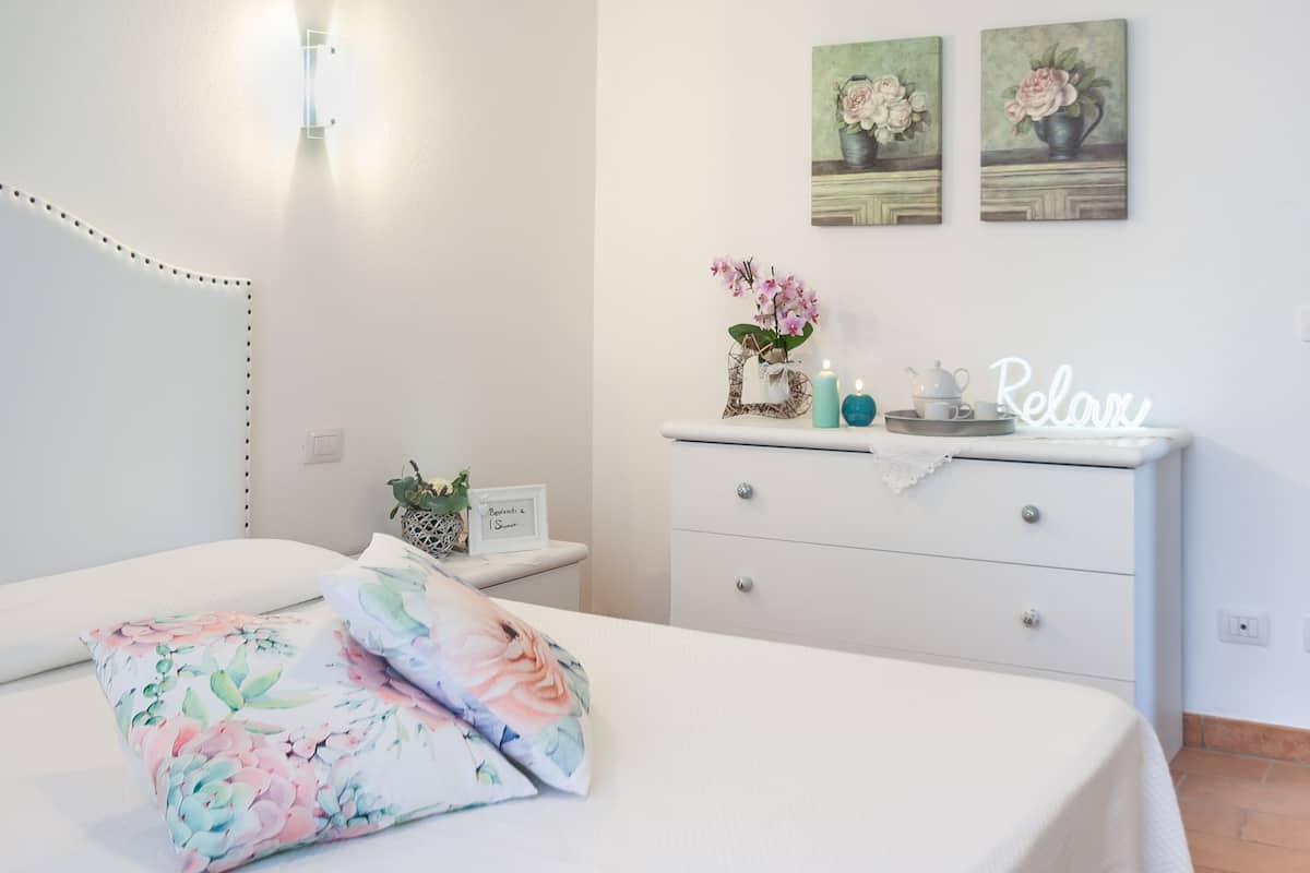 Une chambre à coucher comprenant un lit, une table de chevet, une commode et des œuvres d’art accrochées au mur.