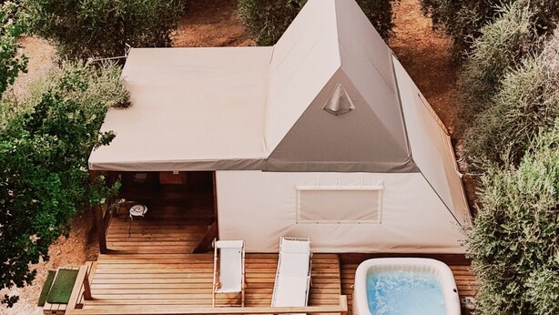 A modern, triangular-roofed outdoor structure with a hot tub, wooden deck, and lounge chairs. - Saturnia Glamping - Seme di Carota (Manciano)