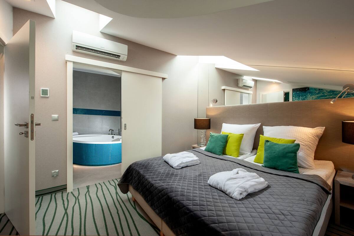 Une chambre d’hôtel avec un lit, une salle de bain avec une baignoire et un appareil de climatisation.