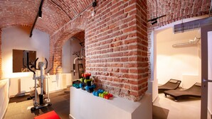 Une salle de sport équipée de matériel d’exercice, avec un tapis rouge et un mur en briques.