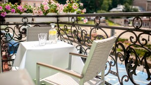 Un balcon avec une table et des chaises, une bouteille d’eau et un verre.