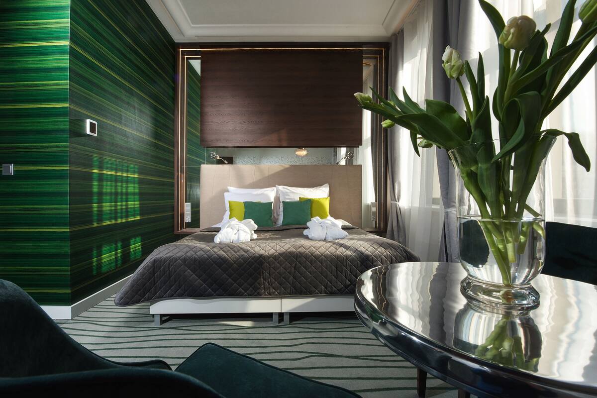 Une chambre d’hôtel moderne avec un grand lit, une table en verre et un vase de fleurs.