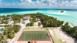 Vista aérea de una zona costera con un campo deportivo, edificios y una playa.