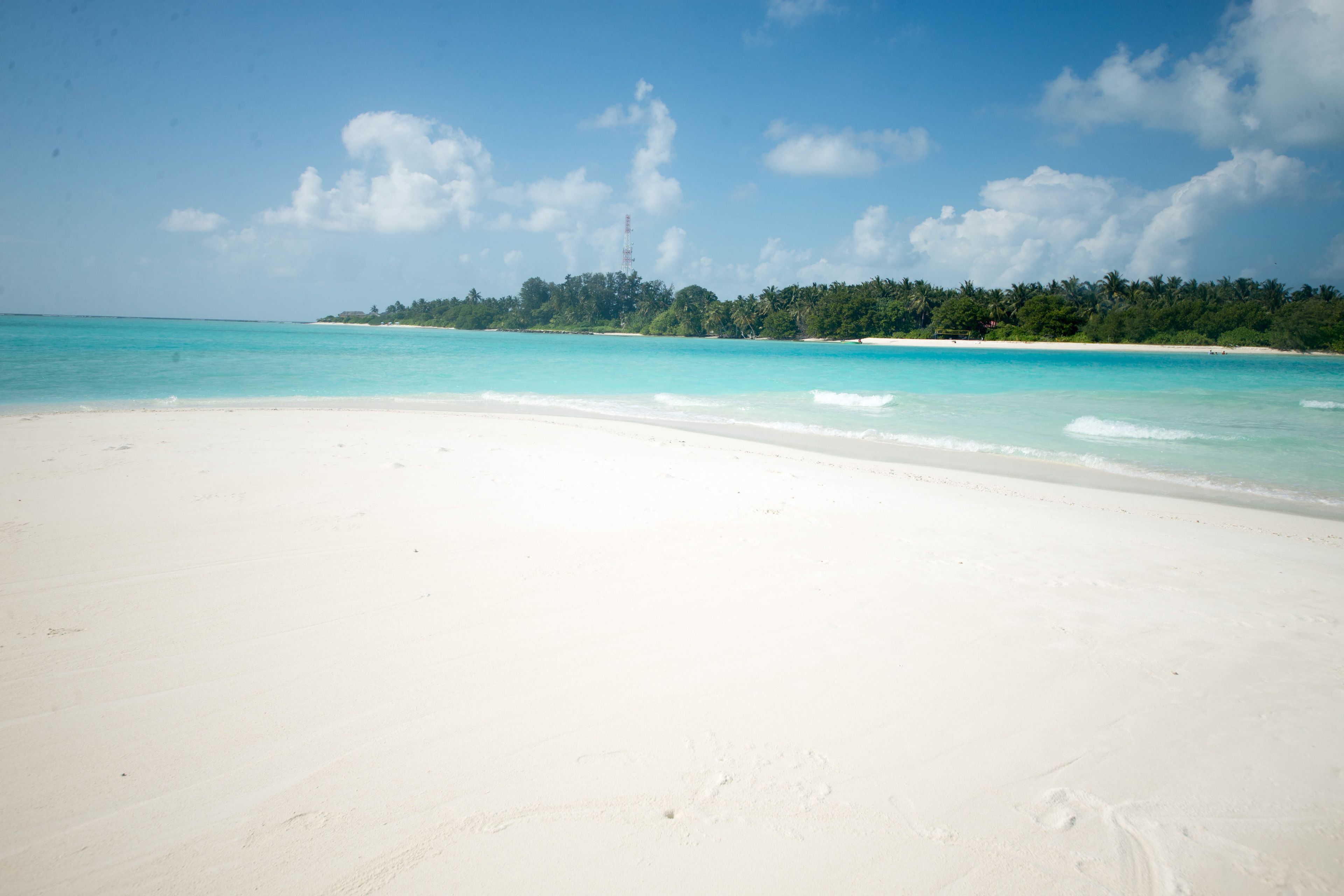A beach with white sand and turquoise water.