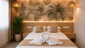 Una habitación de hotel con cama, un mural en la pared, dos lámparas colgantes y una planta en maceta.