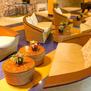 A lounge area with sofas, round wooden tables, and decorative flowers. - Hotel Koral (Varna)