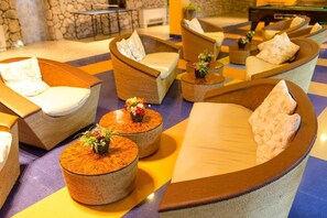 A hotel lobby with curved seating, a stone wall, and a small table with a flower arrangement. - Hotel Koral (Varna)