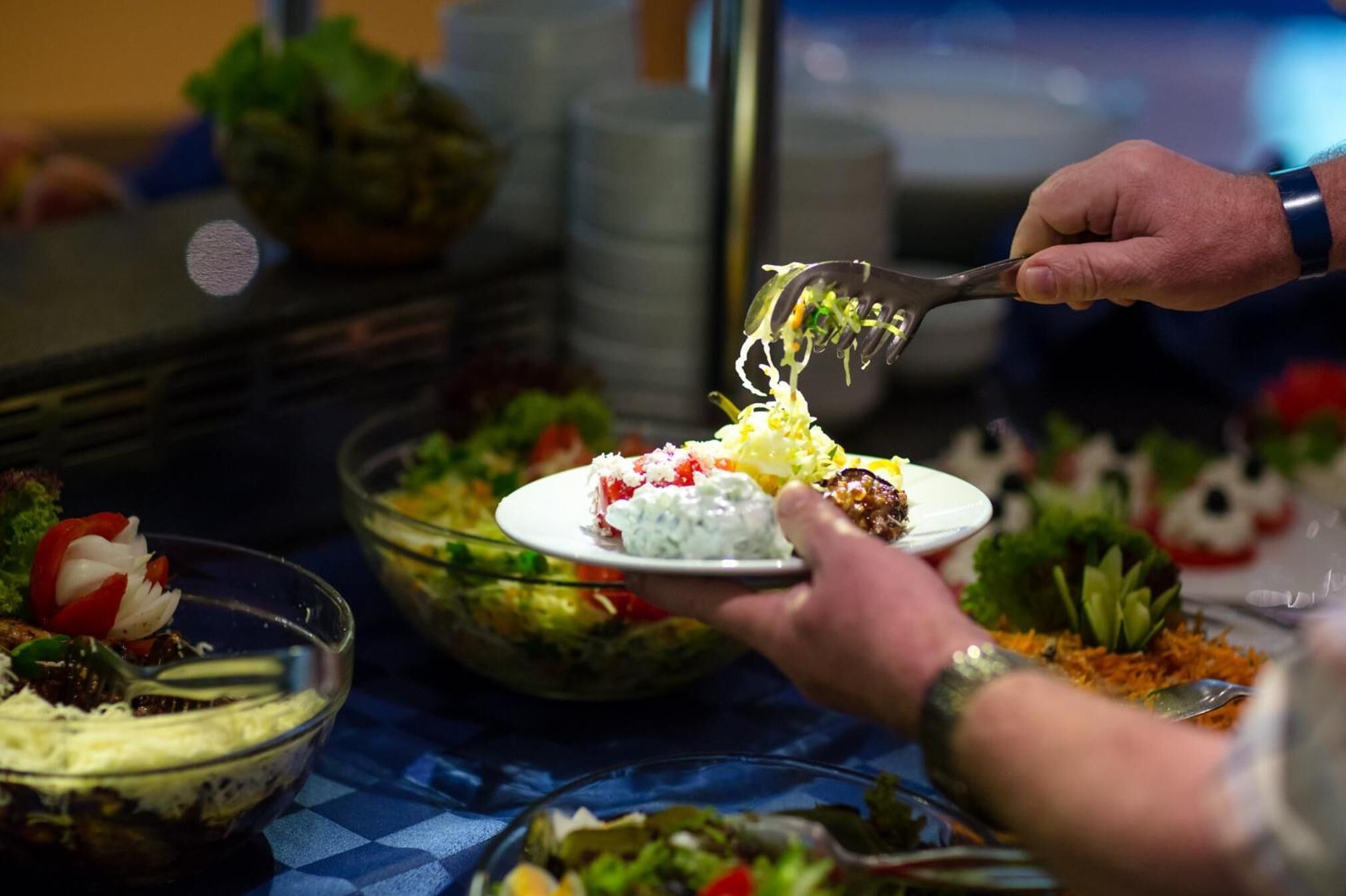 A buffet table with various dishes and a person serving themselves.