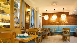 A café interior with wooden furniture, a brick wall, and a blue booth. - Mistral Dom Wakacyjny (Ustka)
