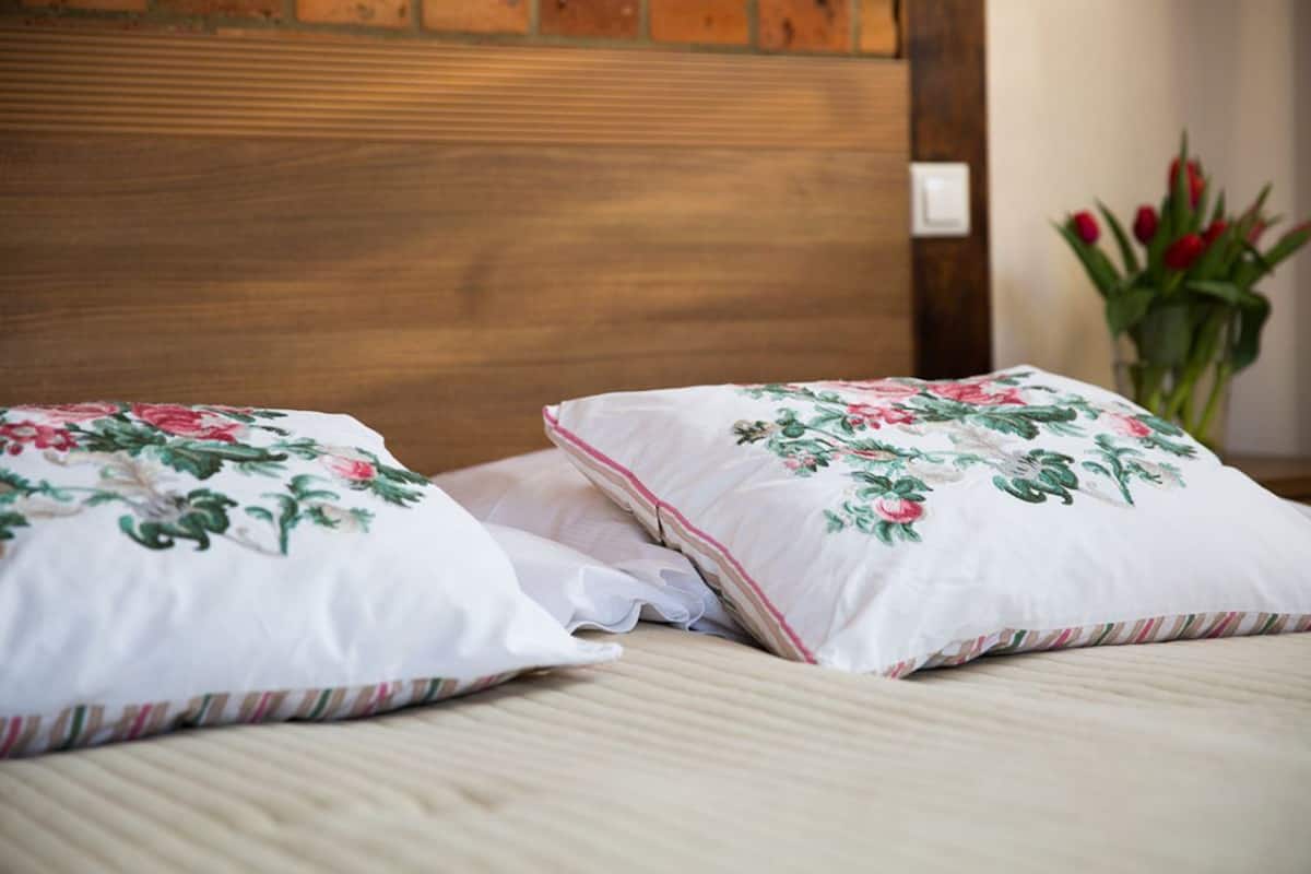 A bed with floral-patterned pillows and a wooden headboard.
