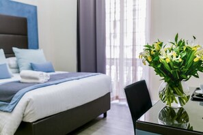 A hotel room with a bed, a glass coffee table, and a vase with flowers. - Bloom Apartment by La Griffe (Rome)