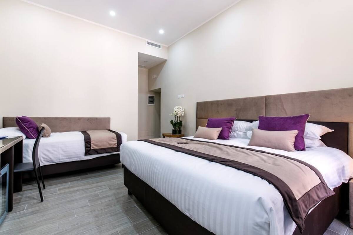 A hotel room with two beds, a desk, and a chair.