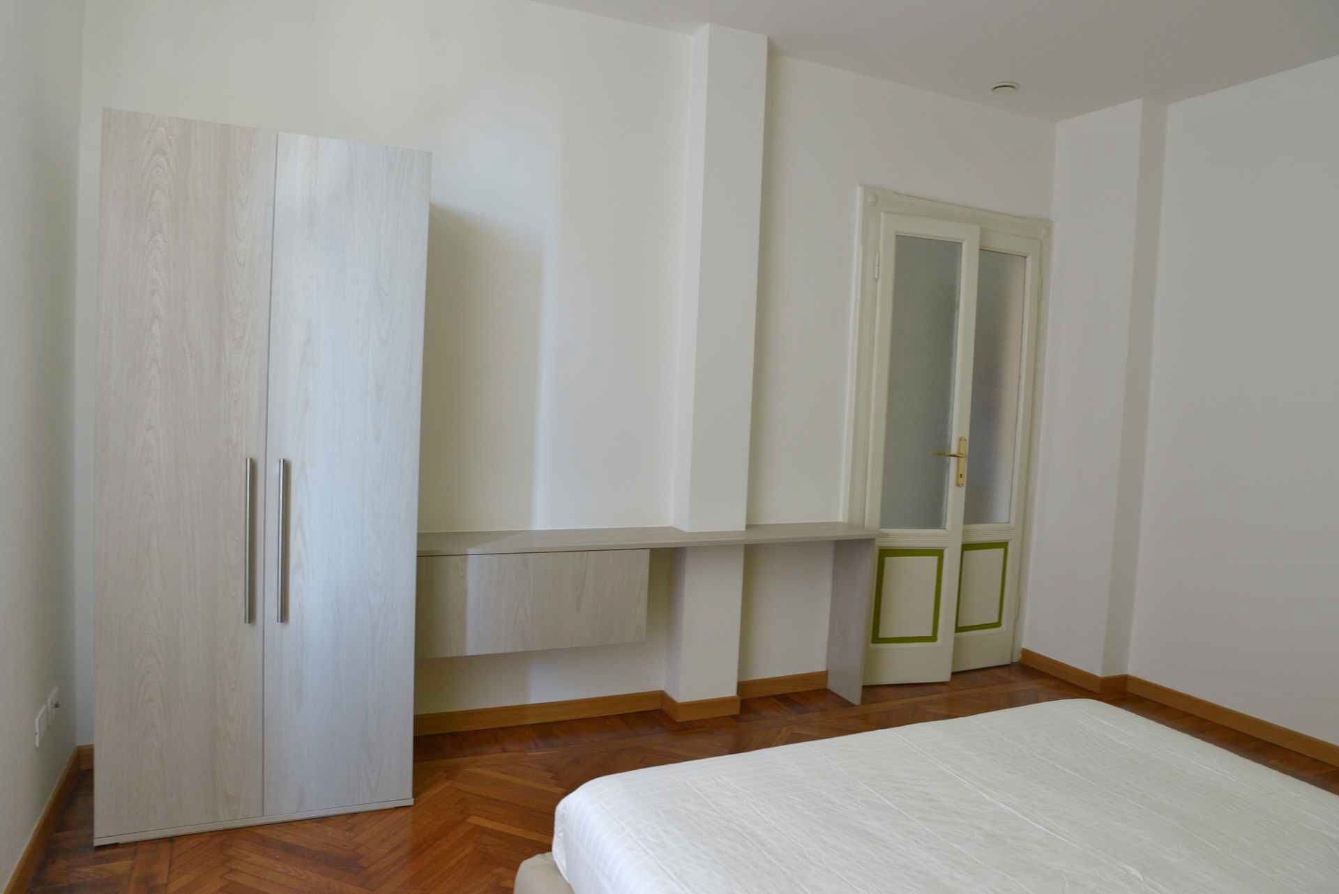 Ein Schlafzimmer mit einem Bett, einem Kleiderschrank und einer Tür mit Spiegel.
