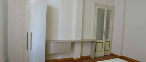 A bedroom with a bed, a wardrobe, and a door with a mirror.