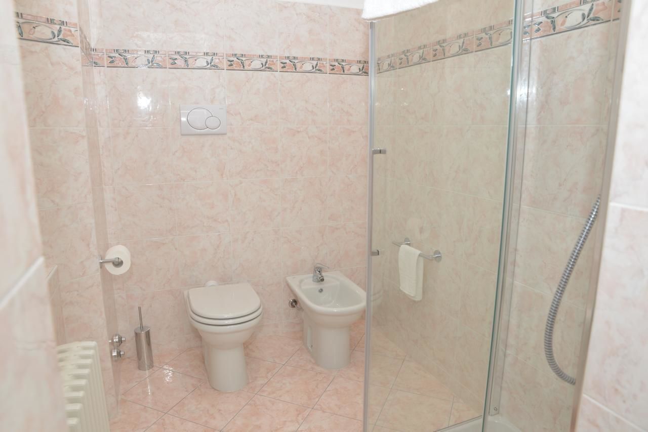 Un baño con inodoro, bidé y ducha con mampara de vidrio.