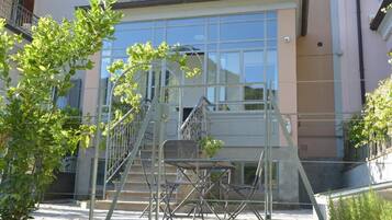 Un edificio con facciata in vetro, scala in metallo e area salotto all'aperto.