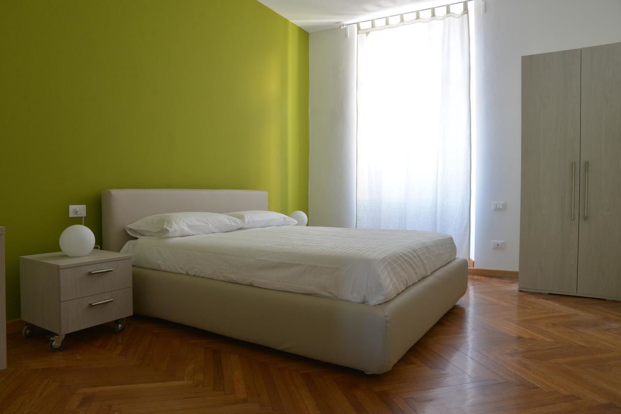 Une chambre à coucher comprenant un lit, une table de chevet, une armoire et une fenêtre avec des rideaux.