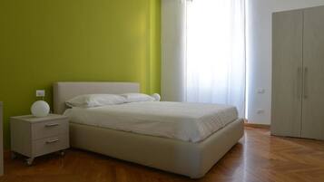 Une chambre à coucher comprenant un lit, une table de chevet, une armoire et une fenêtre avec des rideaux.