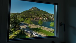 Blick aus einem Fenster eines Gebäudes auf einen See, einen Parkplatz und einen Hügel mit Gebäuden.