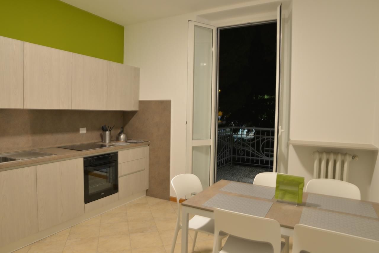 Une cuisine moderne avec un coin repas, une porte-fenêtre coulissante donnant sur un balcon et une vue sur le paysage urbain nocturne.