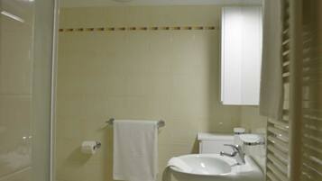 A small, compact bathroom with a toilet, sink, and shower area.