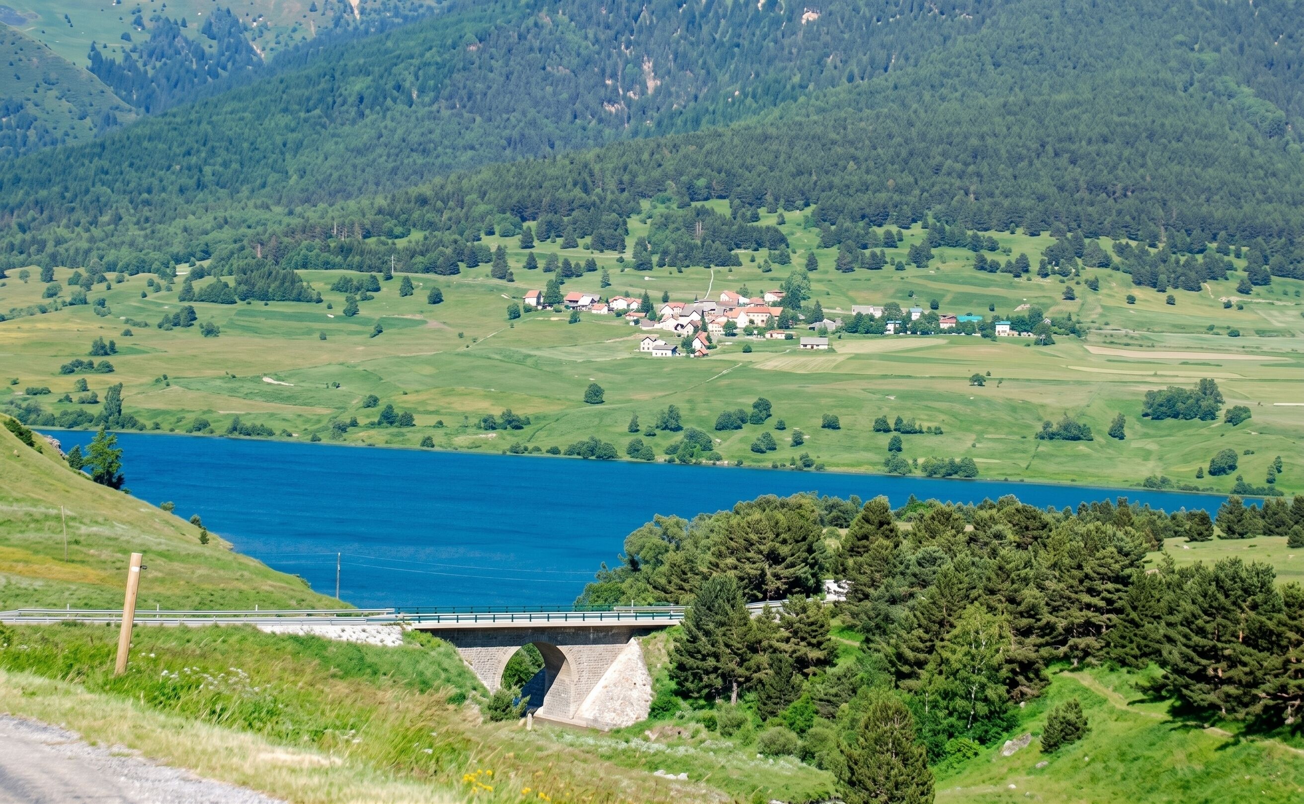 Un pont enjambant un lac, avec un village en arrière-plan.