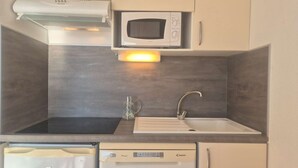 Une cuisine compacte équipée d’un four à micro-ondes, d’un évier et d’un lave-vaisselle.