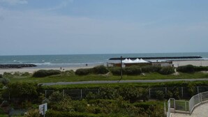 Une vue sur la côte, avec une plage, une tente blanche et un bâtiment au loin.