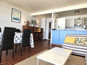 En stue med sofa, spisebord med stole, et køkken og en gang.