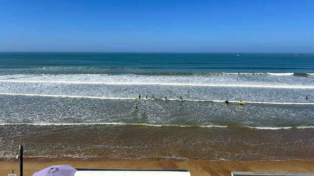 Une plage avec des vagues, un ciel dégagé et un rivage sablonneux.