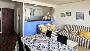 Une pièce de taille modeste comprenant une table à manger, un canapé à rayures et un coin cuisine.