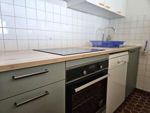 Eine Küche mit Arbeitsplatte, Spüle, Schränken und einem Backofen.